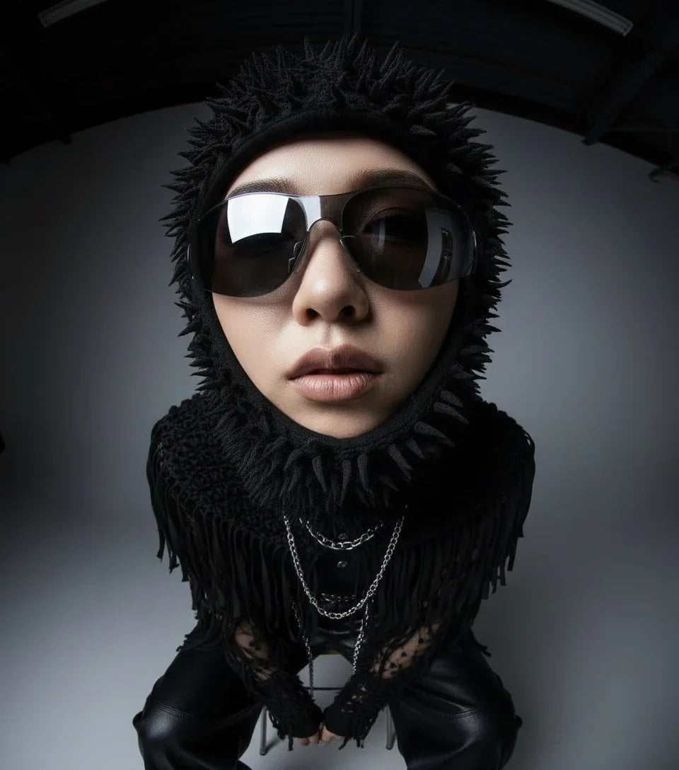 Model in edgy black textured hood, sunglasses, silver chains, and sharp minimal opium fashion.