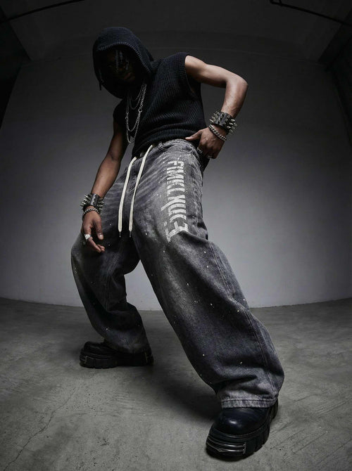 Person wearing a black hoodie and gray pants with white text, standing against a dark background.