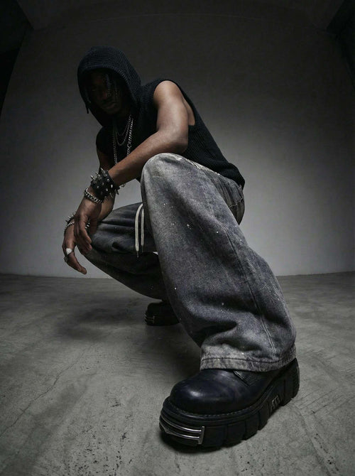 Person wearing a black hoodie, black shirt, gray pants, and black shoes in a dark room.