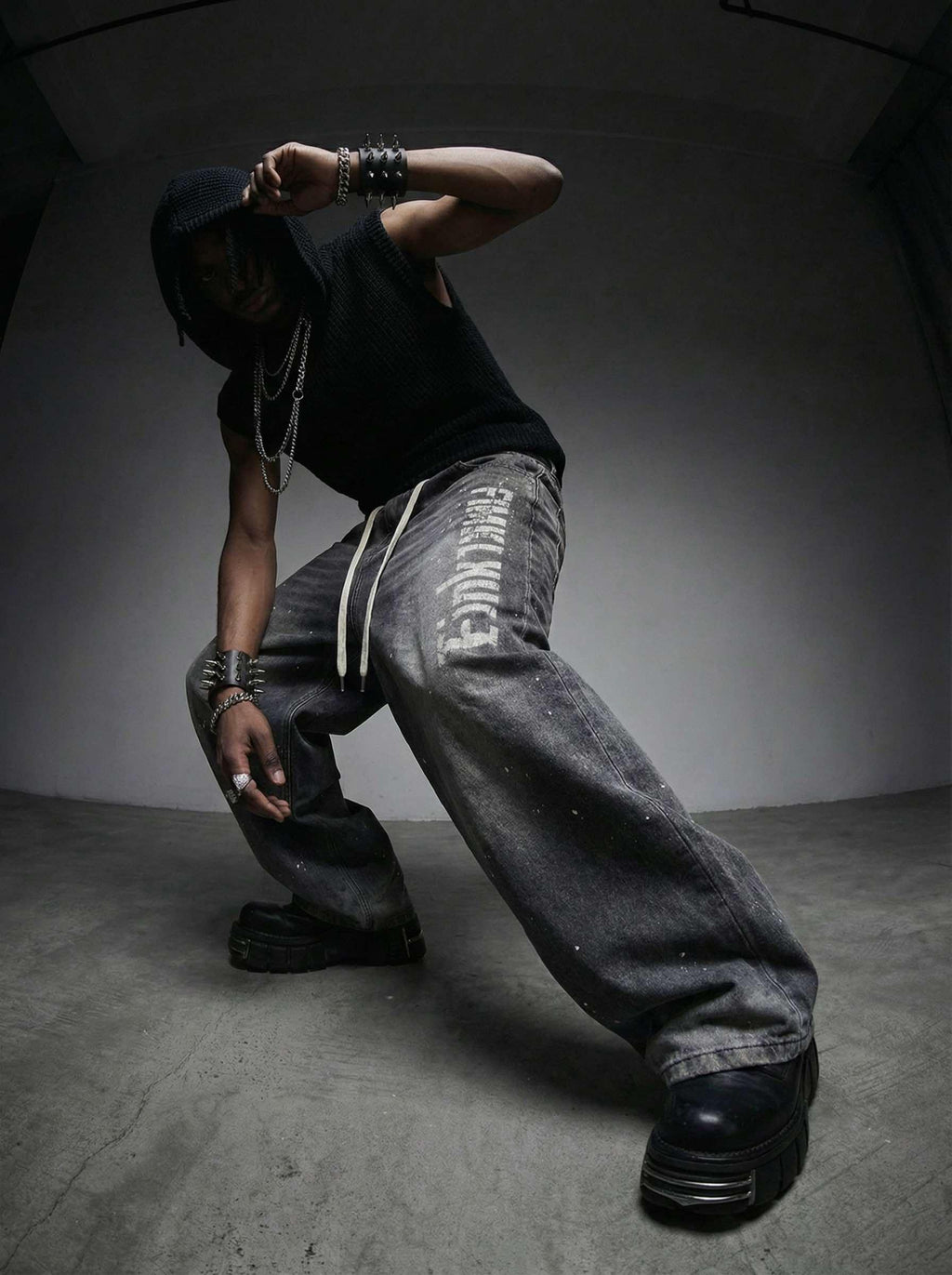 Person wearing a black hoodie, black shirt, and gray pants in a dark room.