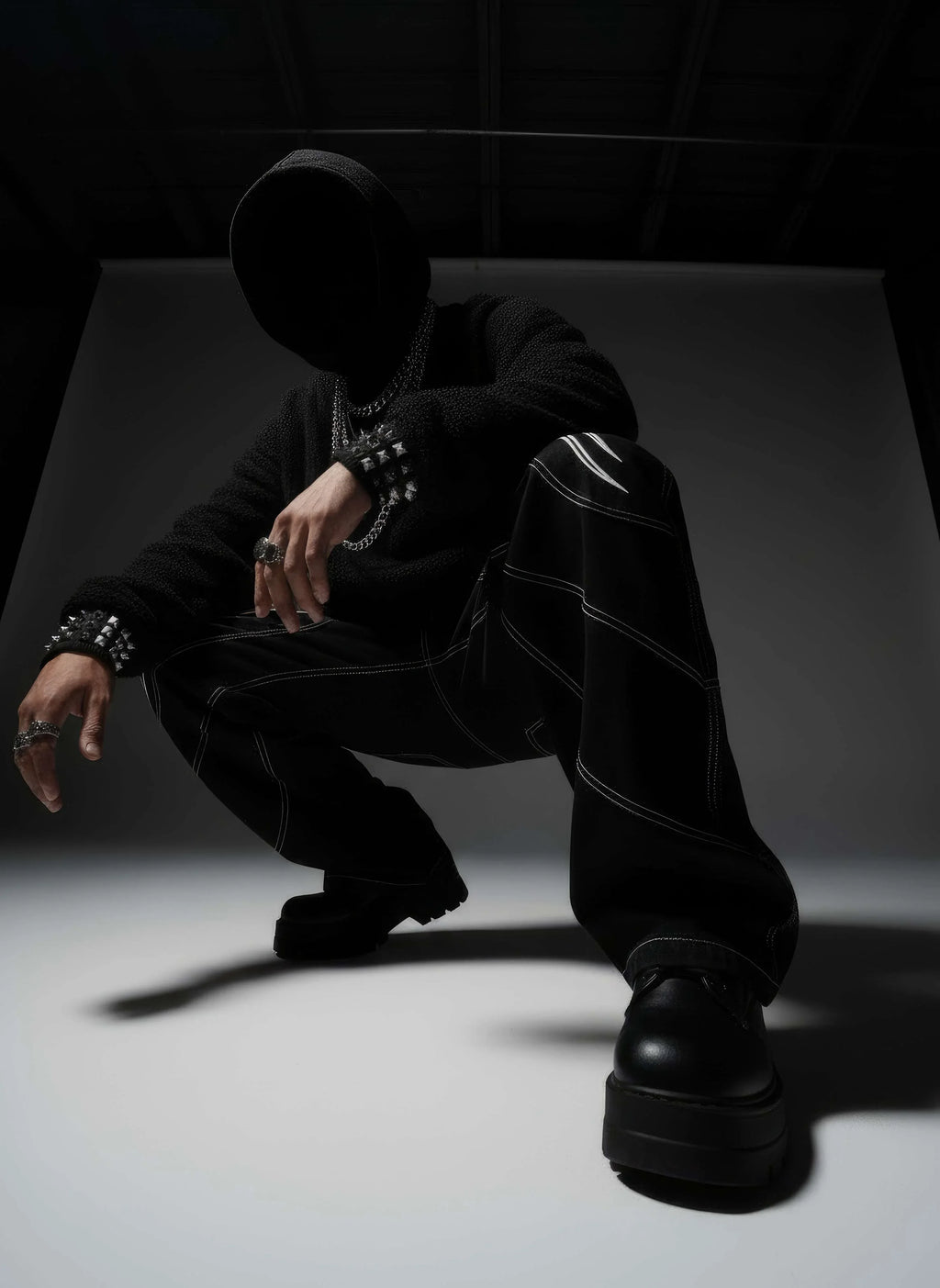 Person wearing a black outfit with platform shoes in a dark setting